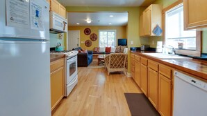 A kitchen with wooden cabinets, a microwave, and a refrigerator. There is a dining area with a table and chairs. - Aspen House- Sweet, Modern Downtown Cottage, 100+mbps Wifi, A/C, Walk Everywhere (Bend)