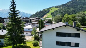 Un bâtiment moderne doté d’un toit plat, entouré d’une végétation luxuriante et adossé à un paysage montagneux.