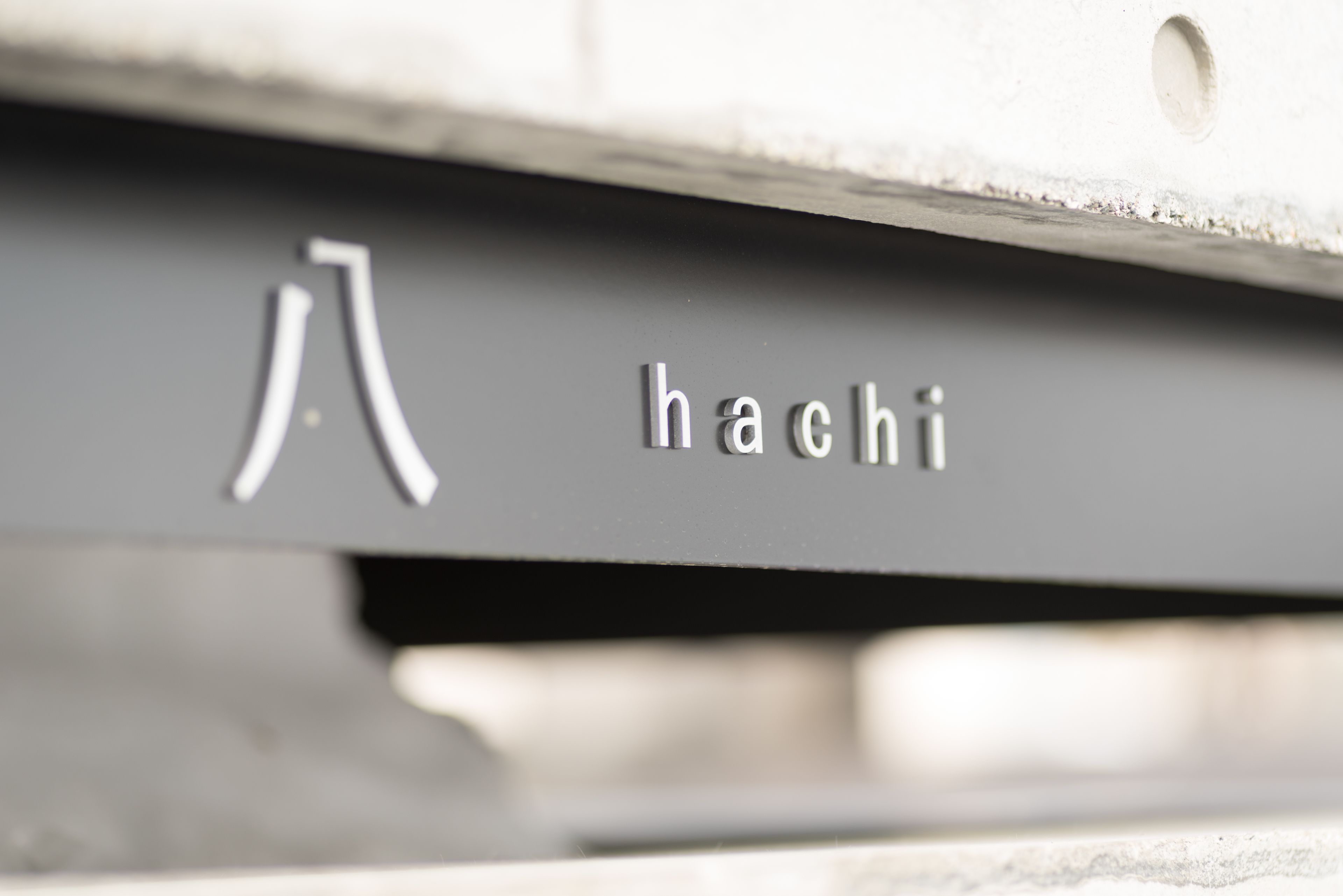 A close-up of a metallic surface with the word "hachi" engraved on it.
