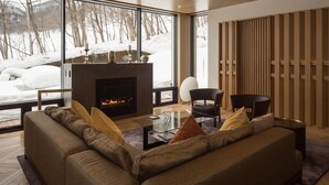 Una sala de estar moderna con chimenea, ventanas amplias y un rincón de descanso acogedor.