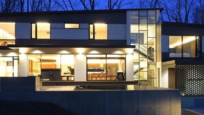 Una casa moderna de dos pisos con amplios ventanales, una escalera a la vista y un interior bien iluminado.