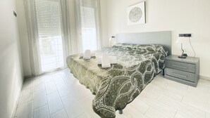 A bedroom with a bed, a nightstand, a lamp, and a window with curtains.