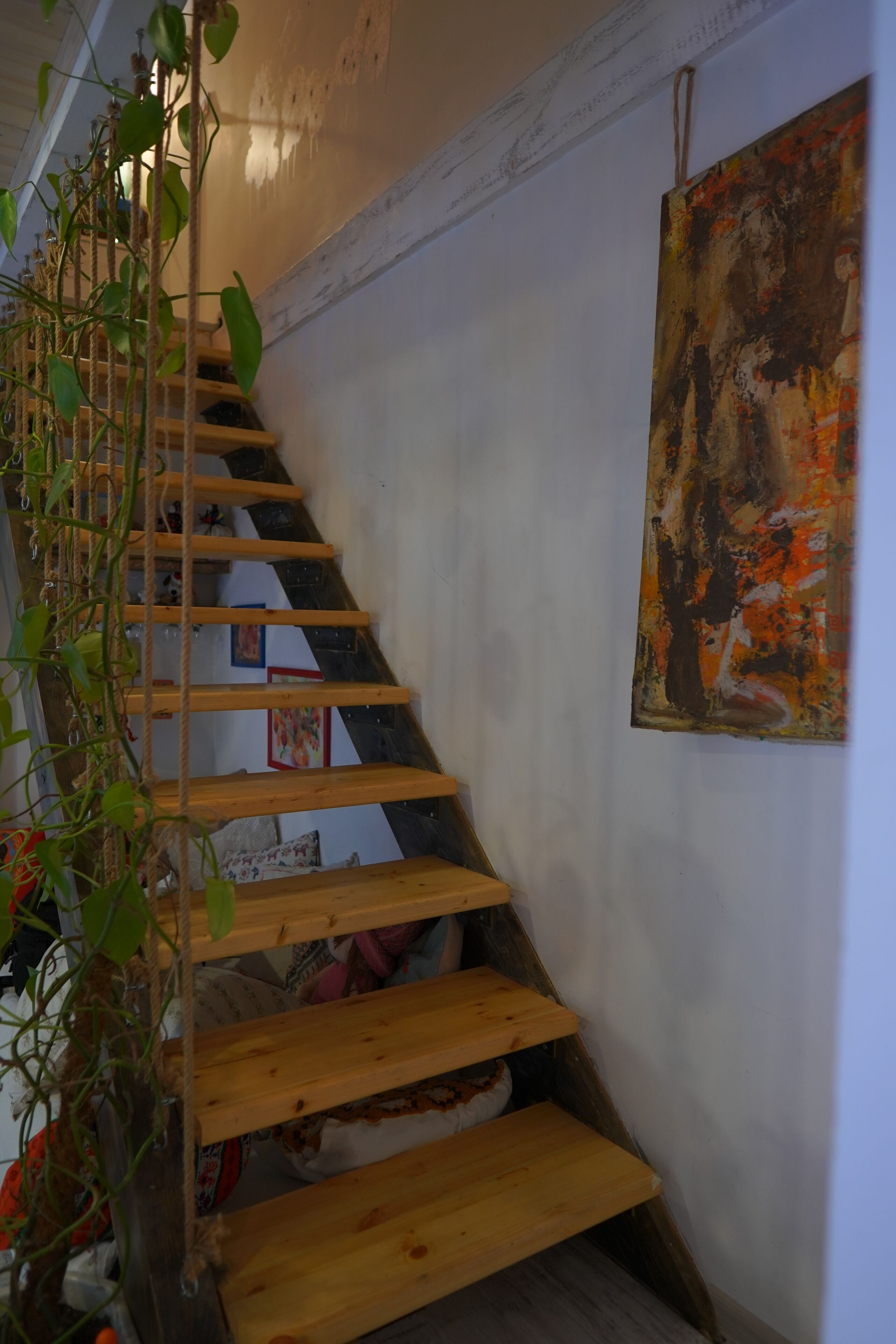 A room with a sloped ceiling, wooden beams, and a hanging artwork.
