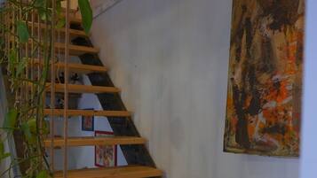 A room with a sloped ceiling, wooden beams, and a hanging artwork.