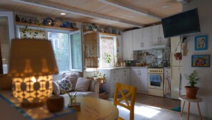 A cozy kitchen with wooden cabinets, a dining table, and a TV mounted on the wall. - Helen and David's apartment,, Bird's nest" (Didube-Chugureti)