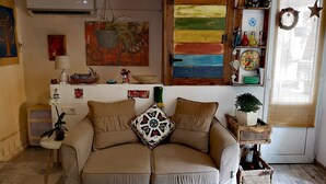 A cozy living room with a beige sofa, a wooden ceiling, a colorful abstract painting, and a window with a star decoration. - Helen and David's apartment,, Bird's nest" (Didube-Chugureti)