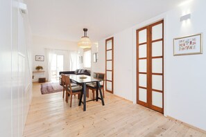 A dining area with a wooden table and chairs, a hanging light fixture, and a sliding glass door.