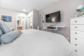 A bedroom with a large bed, a TV mounted on the wall, a dresser, and a mirror. - Promo! Beautiful Oceanfront Condo, Wifi, HDTV, DVD, Hot Tub and Indoor Pool! (Depoe Bay)
