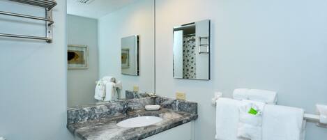 A bathroom with a marble sink, a toilet, a towel rack, and a mirror.