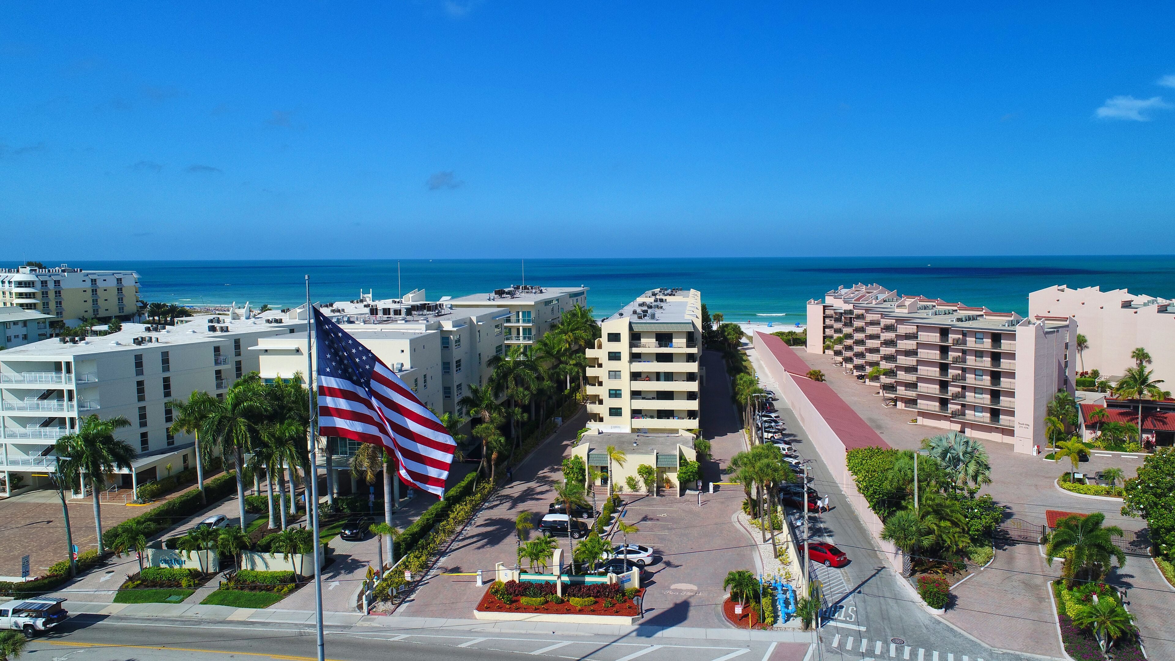 A hotel with multiple floors, a parking area, and a view of the ocean.