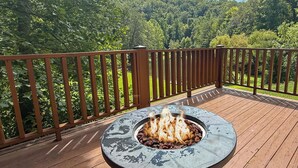 Eine Terrasse mit Feuerstelle in der Mitte, umgeben von einem Holgitter.