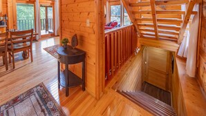 Ein Holzblockhaus mit Essbereich, einem kleinen Tisch mit Pflanze und einer Treppe zu einem Erker.