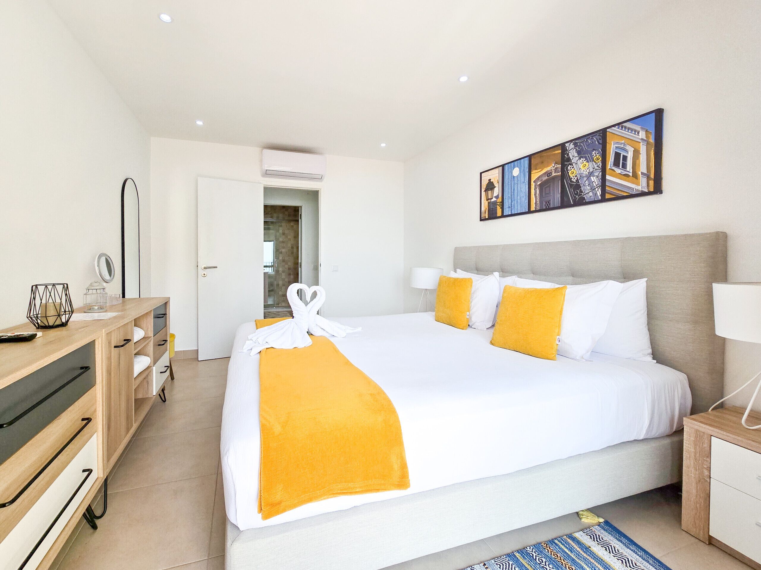 Een hotelkamer met een bed, een bureau, een spiegel en een schilderij aan de muur.