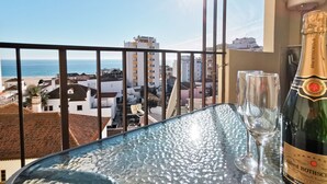 A balcony with a glass table, a bottle of champagne, and two glasses. - Flat Praia Rocha Sea View Sand (Portimão)