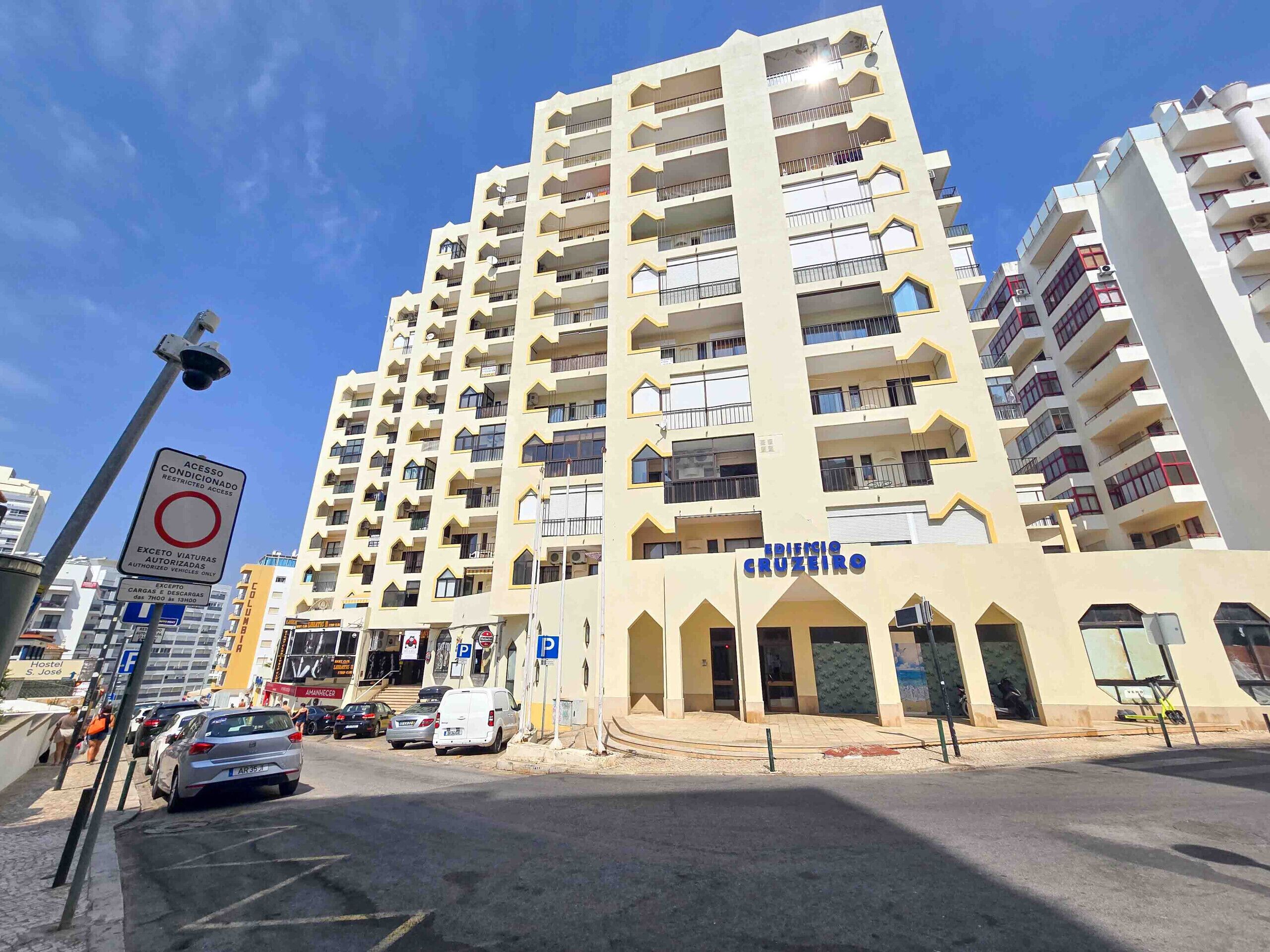 A multi-story building with balconies, a sign indicating restricted access, and a visible entrance with a sign reading "EDIFICE CRUZEIRO".