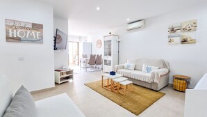 A modern living room with a sofa, coffee table, and a dining area with chairs and a table. - Flat Praia Rocha Sea View Sand (Portimão)