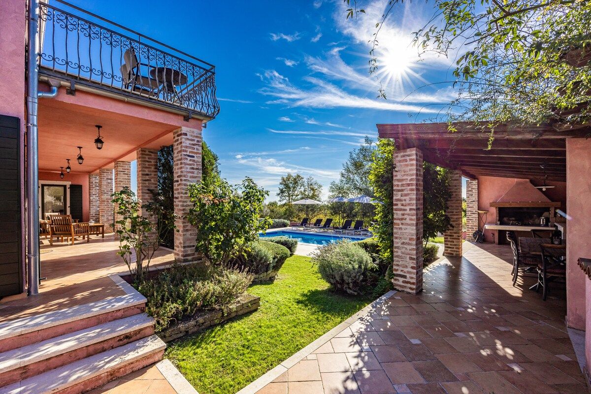 A residential property with a swimming pool, outdoor seating, and a covered patio area.