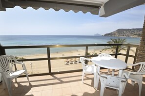 A balcony with a view of the beach, white plastic chairs, and a table. - A06 CALPEMAR A 5º 19 (Calpe)