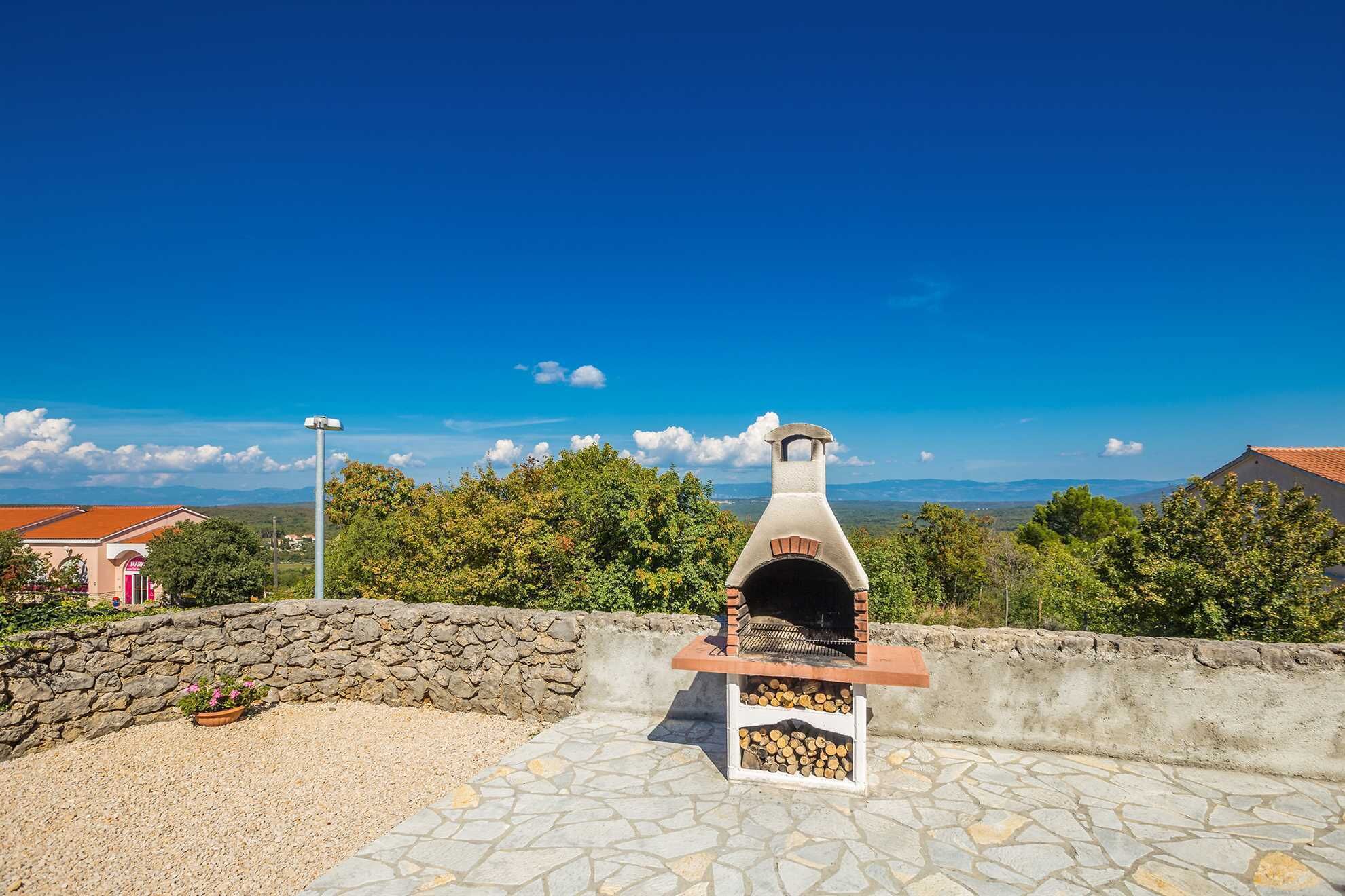 Un horno de ladrillo al aire libre con pared de piedra y camino de grava.