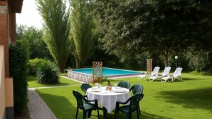 Un espace aménagé au bord de la piscine, avec une table et des chaises, une piscine et des chaises longues.