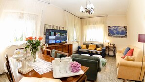 Un salon équipé d’un téléviseur, d’un canapé et d’un coin repas avec une table mise pour deux personnes.