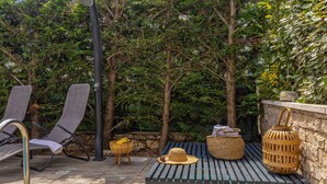 Un espace extérieur aménagé avec deux fauteuils de jardin, un banc en bois et un panier en osier.