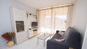 Un salon comprenant un canapé, une table basse, un téléviseur et un meuble avec des étagères.