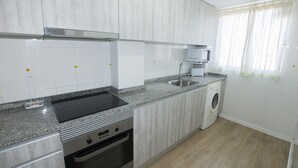 Une cuisine moderne avec des meubles blancs, un plan de travail en granit, un four à micro-ondes encastré et un lave-linge.