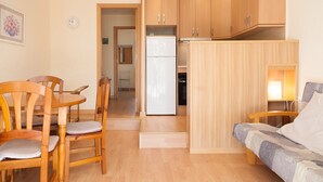 A compact living space with a dining area, kitchenette, and a sofa. - Apartment with Pool in Cala Crancs area · UHC CASAS BLANCAS 121 (Salou)