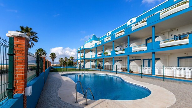 Et hotel med swimmingpool, flere balkoner og en murstensmur.