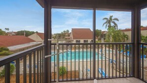A covered pool area with a view of a residential neighborhood, including houses and palm trees. - Partial Beach View 2 bed, 2 bath at Sanibel Moorings #742 (Sanibel)