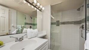 A bathroom with a large mirror, a sink, a toilet, and a shower area. - Partial Beach View 2 bed, 2 bath at Sanibel Moorings #742 (Sanibel)