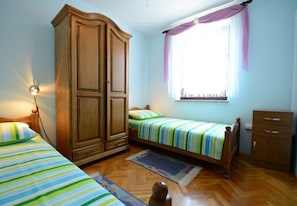 A bedroom with two beds, a wardrobe, a window with curtains, and a nightstand with a lamp. - Apartment Filipin in Porec, Istria (Porec)
