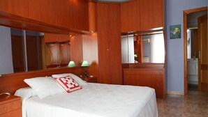 Un dormitorio con una cama grande, un armario de madera y un espejo.