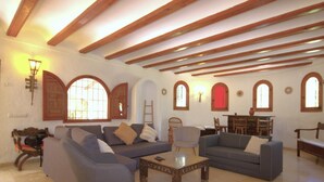 A spacious living room with high wooden beams, a fireplace, and a dining area with wooden furniture. - La Cartuja - Javea, Costa Blanca (Javea)