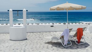 A beachside lounge with a white column, a swing, and a beach umbrella. - Eufemia, Casa Rural Caleton del Golfo, El Golfo (El Golfo)