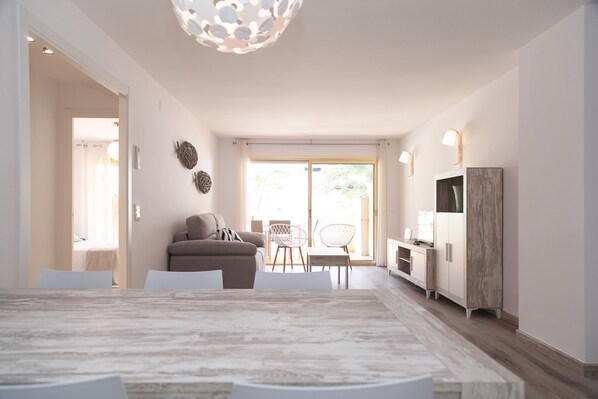 Een moderne woonkamer met een marmeren eettafel, een bank en een tv-meubel.
