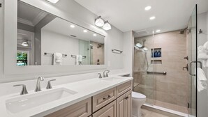 A modern bathroom with a large mirror, dual sinks, and a glass-enclosed shower area. - Newly Renovated Garden View 2 bed, 2 bath at Sanibel Moorings #1131 (Sanibel)
