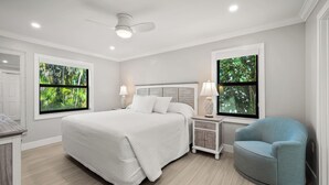 A bedroom with a large bed, two nightstands, a chair, and a ceiling fan. - Newly Renovated Garden View 2 bed, 2 bath at Sanibel Moorings #1131 (Sanibel)