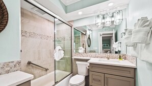 A modern bathroom with a glass shower enclosure, a bathtub, a toilet, and a vanity with a large mirror.