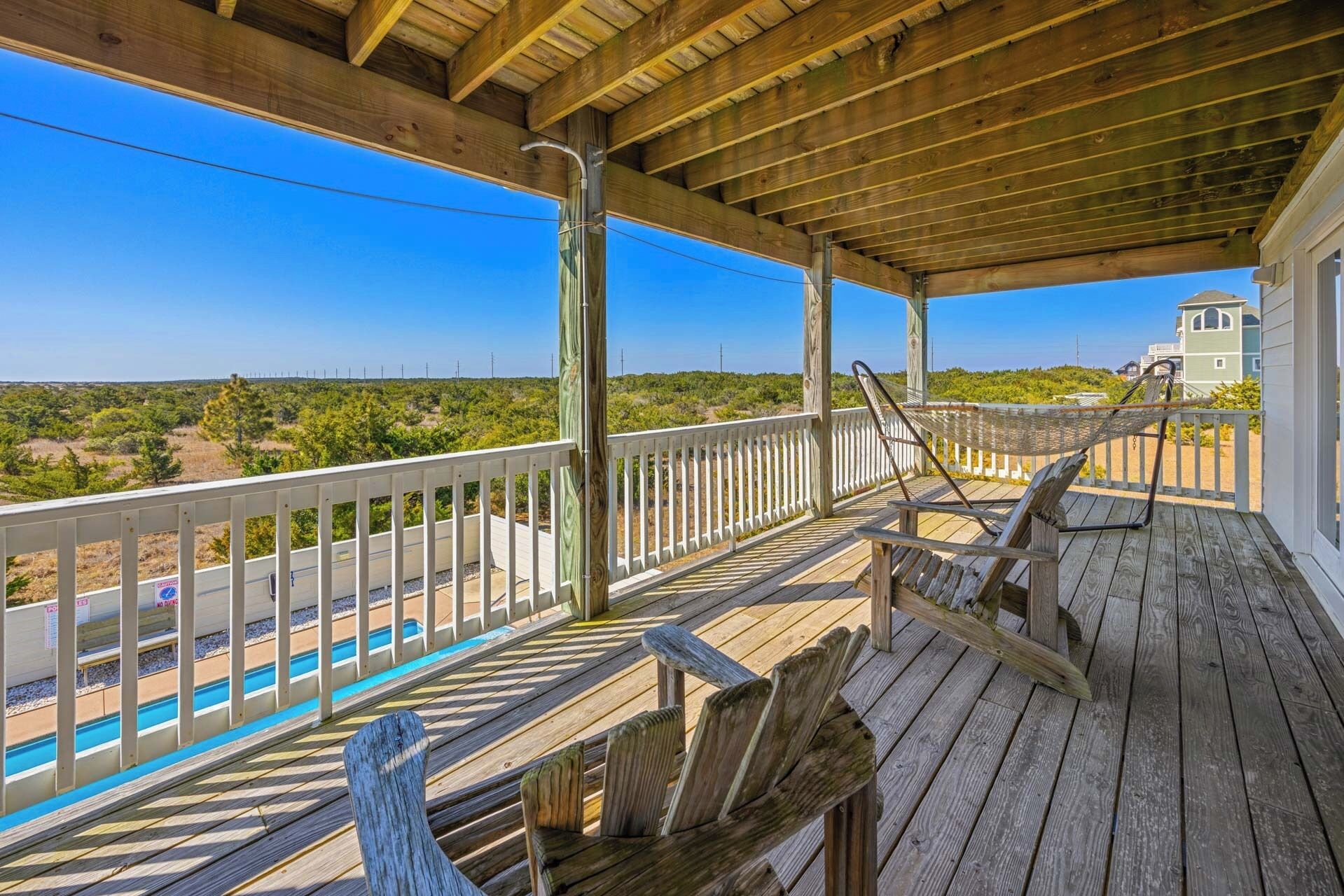 A wooden deck with a view of a beach and a lighthouse.