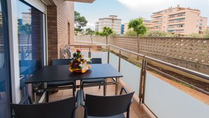 Ein Balkon mit Tisch und Stühlen, einer Blumenkomposition und Blick auf Gebäude und Bäume.
