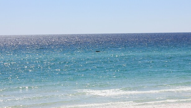 Une plage avec une eau d’un bleu limpide et un rivage sablonneux.