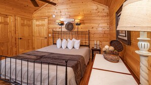 Een houten slaapkamer met een bed, een plafondventilator, wandlampen en een decoratieve mand op het nachtkastje.