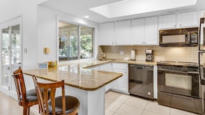 A modern kitchen with white cabinets, a granite countertop, stainless steel appliances, and a large window providing natural light. - 2 BR with a Loft and Beach Service in Private Resort Community (Miramar Beach)