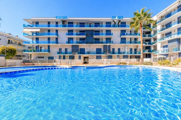 A multi-story hotel with a swimming pool in the foreground.