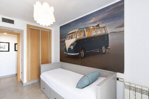 Een slaapkamer met een bed, een radiator aan de muur en een grote muurschildering met een busmotief.