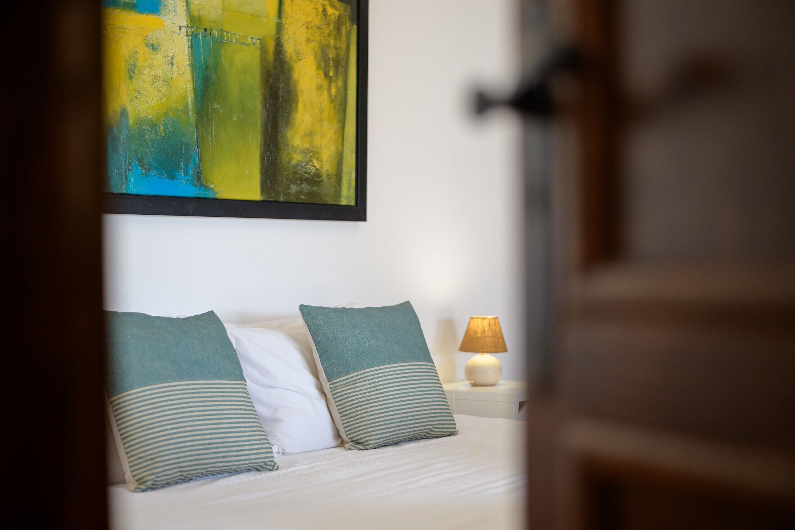 Un lit avec deux oreillers, une lampe de chevet et un tableau au mur.
