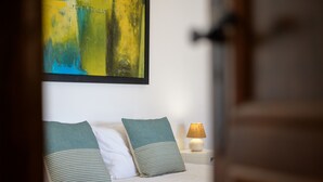 Een bed met twee kussens, een bedlampje en een schilderij aan de muur.