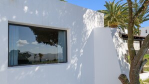 Een modern gebouw met een groot raam dat een berglandschap weerspiegelt.